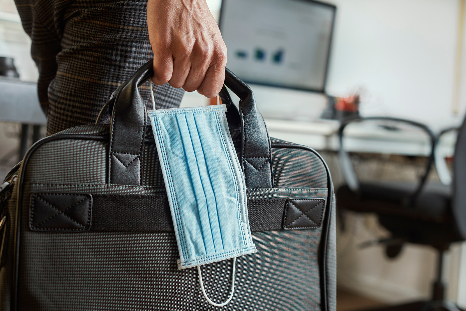 closeup of a young man in an office holding a briefcase and a su